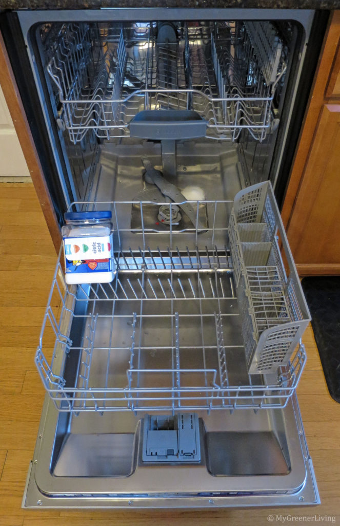 dishwasher with container of citric acid and scoop of citric acid in the tub